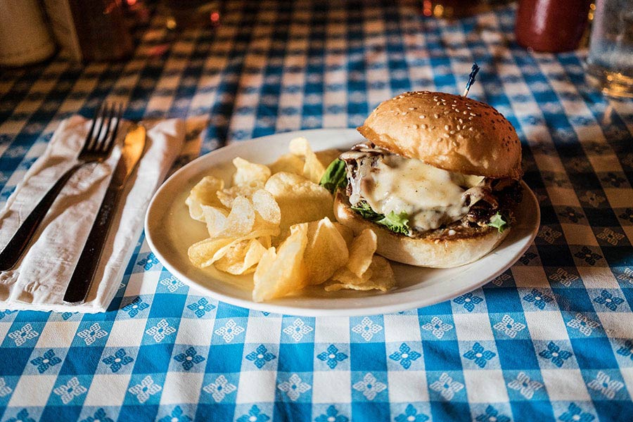 Cheese burger and fries sitting on a plate on a blue gingham table cloth.
