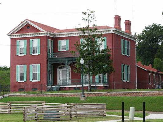 Venue_Moore_Hornor red brick building with mint green shutters on hill with tree and fence
