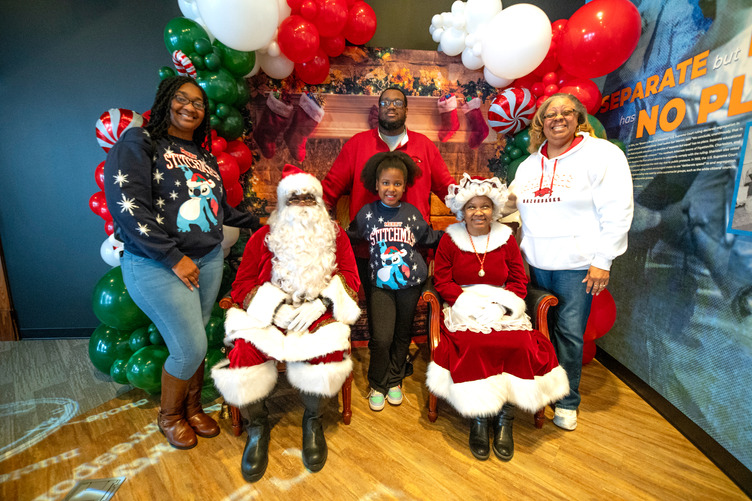 A Black family posing with Santa and Mrs. Claus