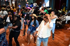 A group of people line dancing in various colored hats