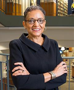 headshot of woman in library wearing coat and glasses