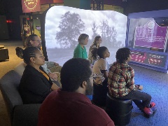 Agroupofadultsandchildrenwatchingavideowithintheexhibit