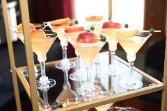 Light yellow-orange drinks in martini glasses with apple slice garnishes