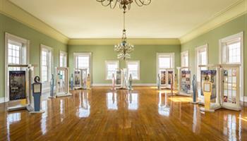 large hall with chandelier, wooden floors, and windows